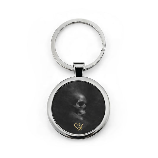 Llavero Veiled Remains Calavera — Llavero redondo de acero inoxidable con calavera ahumada y acento de corazón dorado