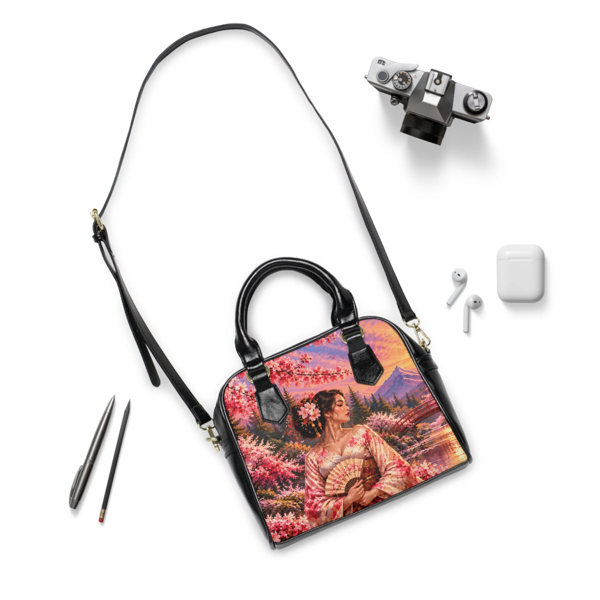 Madama Butterfly — A Thousand Petals shoulder handbag laid flat with its long black strap beside a camera and earbuds.