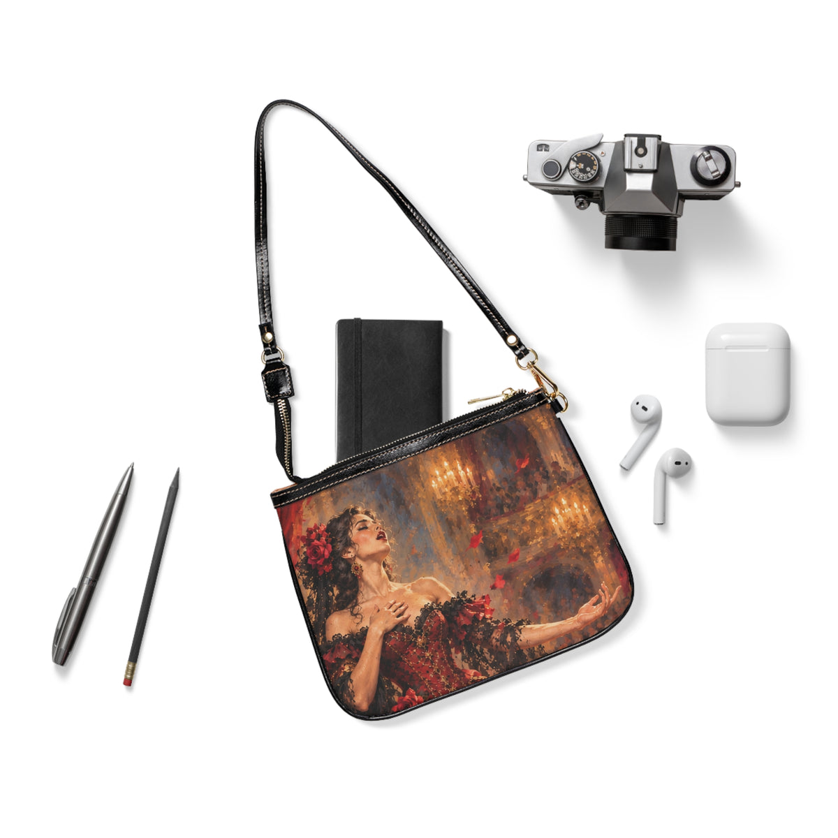 Carmen — The Last Note small shoulder bag laid flat with its black strap beside a camera, notebook and earbuds.