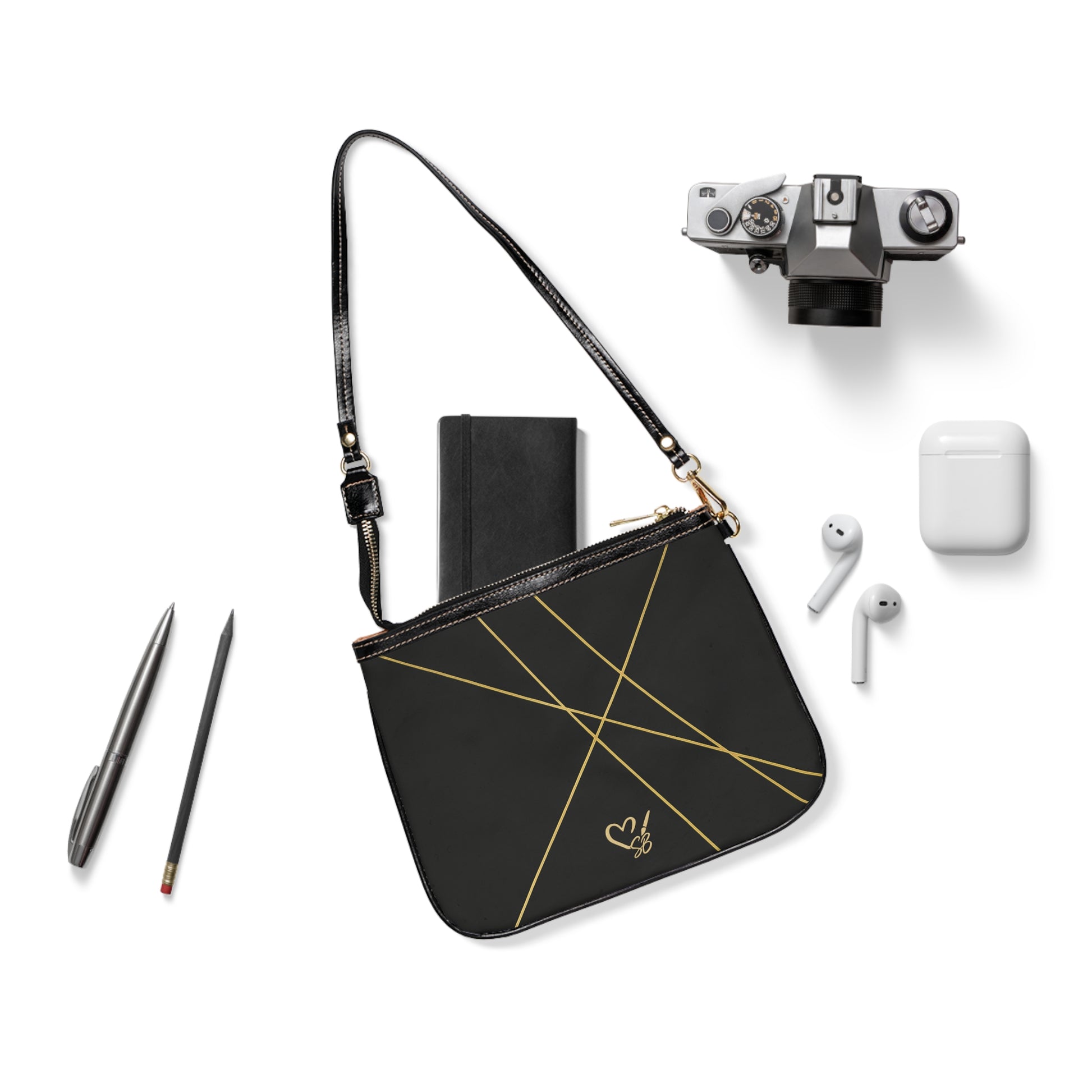 Michelle small shoulder bag flat lay – minimal black crossbody with gold heart accent detail by the Soulful Brush
